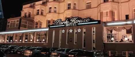 Un hotel llamado 'Park House Hotel' con una fila de coches estacionados en la entrada.