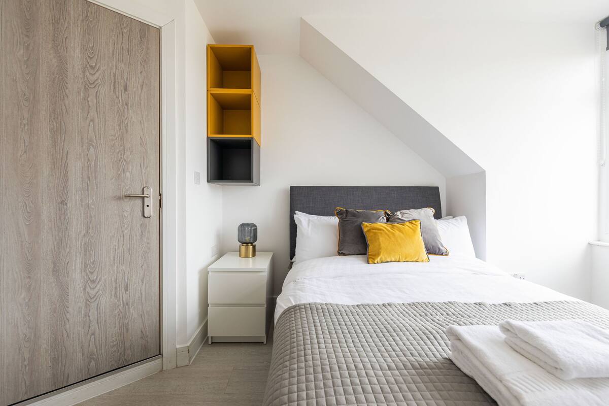 Un dormitorio con cama, mesita de noche, armario y estante empotrado.