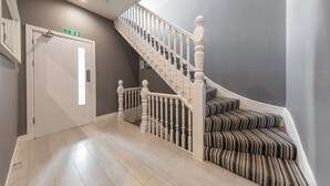 Una escalera con barandilla blanca y alfombra a rayas que conduce a una plataforma.