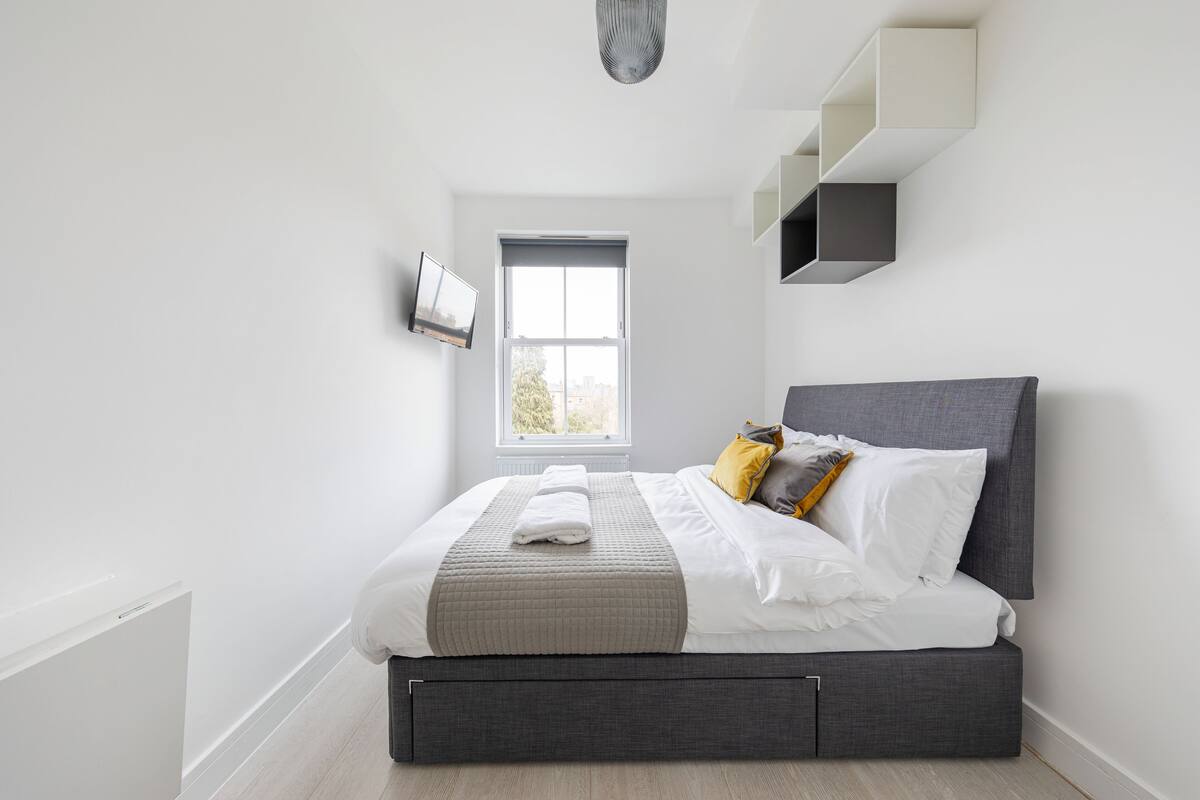 Un dormitorio moderno con cama, ventana y estanterías empotradas.