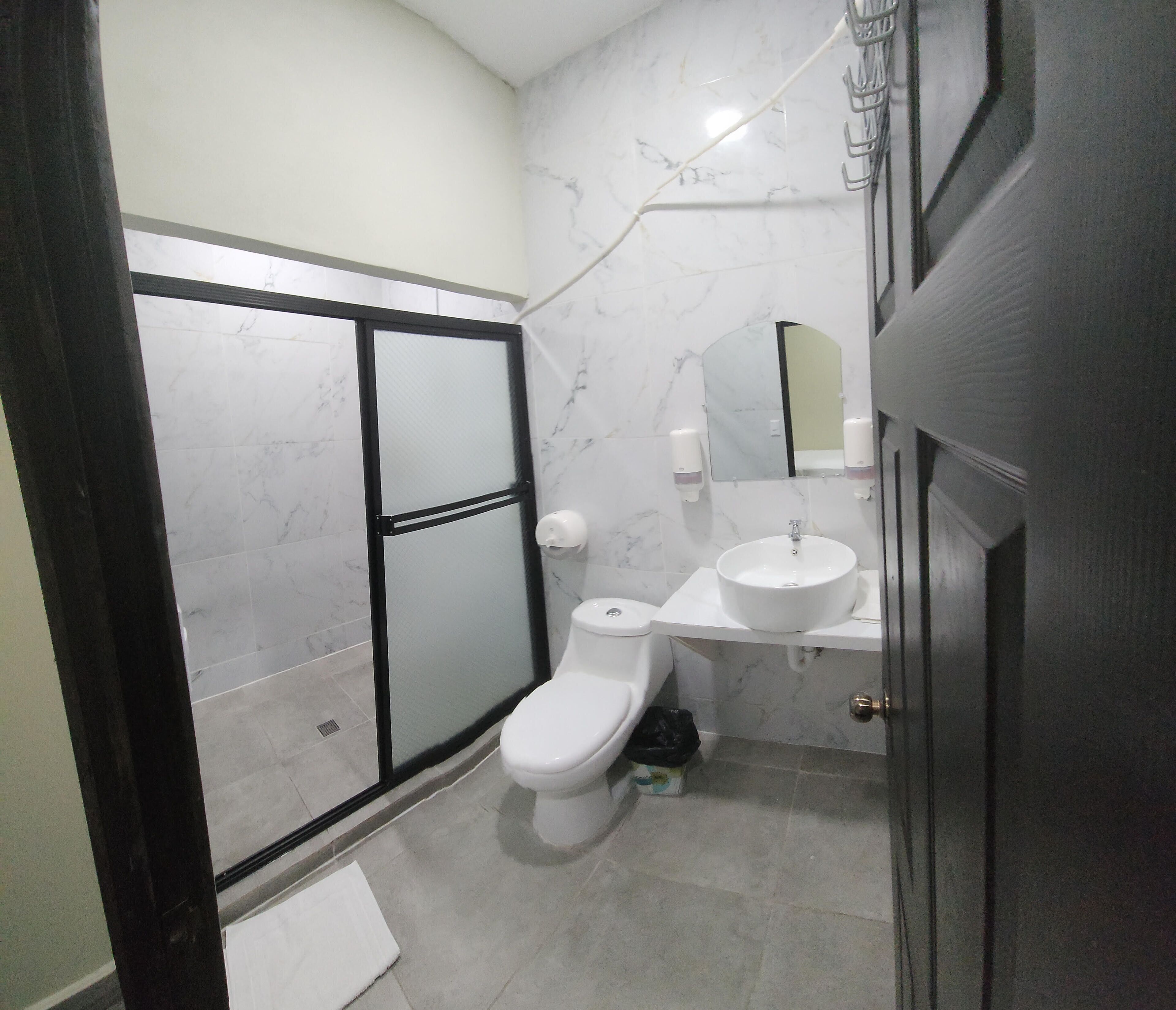 Une salle de bain comprenant des toilettes, un lavabo et un espace douche.