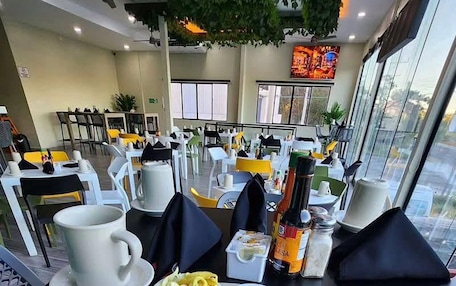 A dining area with tables set for meals, including a plate of food and condiments.