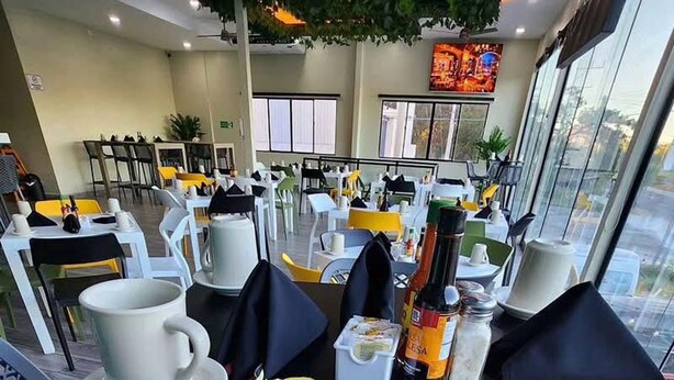 A dining area with tables set for meals, including a plate of food and condiments. - Mi Tierra Aeropuerto Hotel y Restaurante (San Luis Talpa)