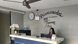 A reception desk with a clock and a sign that reads "Bienvenidos Mi Tierra." - Mi Tierra Aeropuerto Hotel y Restaurante (San Luis Talpa)