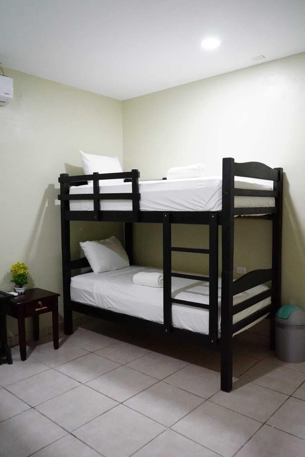 A bunk bed with white bedding in a room with light green walls and tiled flooring.