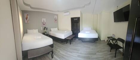 A hotel room with two beds, a flat-screen TV, and a small table with chairs.