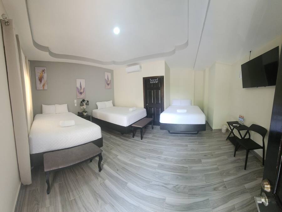 Quarto de hotel com duas camas, uma televisão de tela plana e uma pequena mesa com cadeiras.