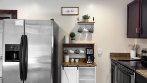 Una cocina compacta con un refrigerador de acero inoxidable, una estación de café y un horno empotrado.