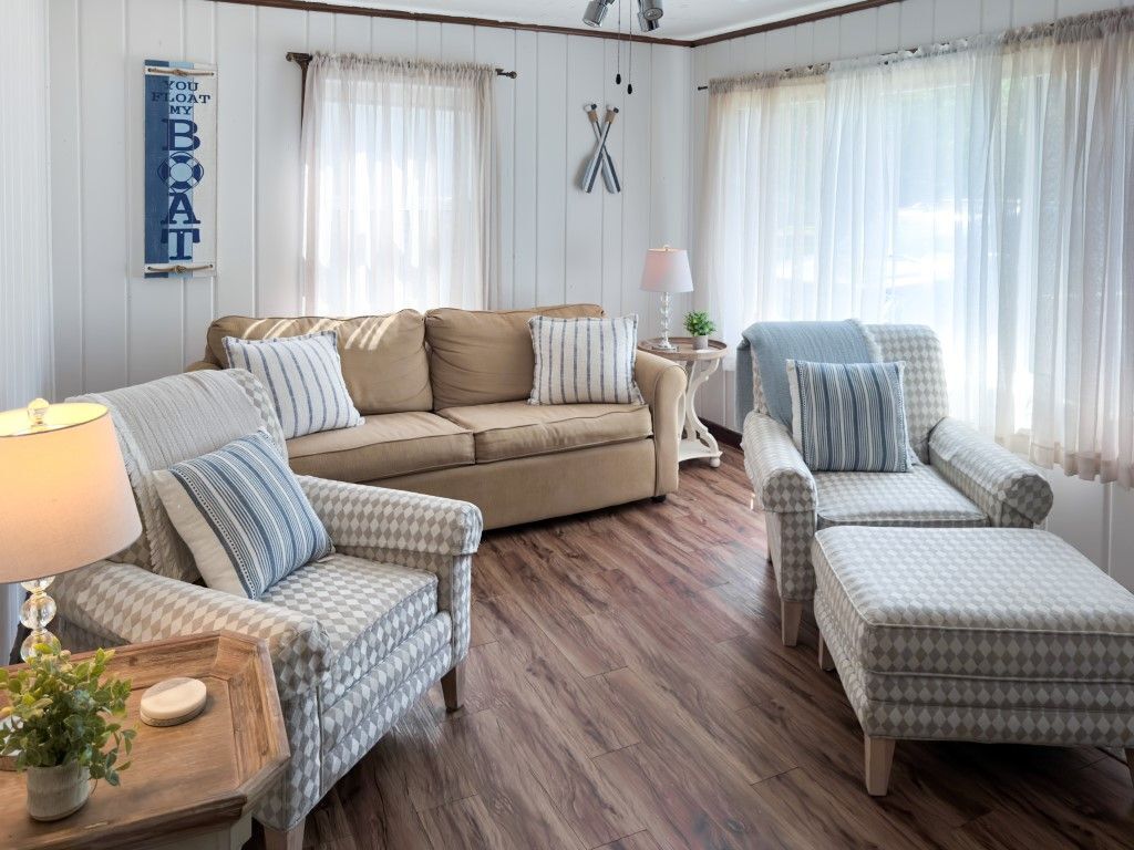 Ein gemütliches Wohnzimmer mit einem beigen Sofa, gemusterten Sesseln und Holzboden.