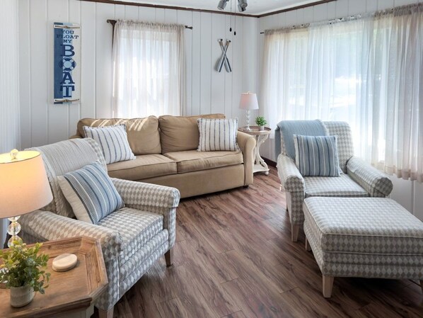 A cozy living room with a beige sofa, patterned armchairs, and a wooden floor. - Private Beach, Bonfire, New Blackstone Grill (Lexington)