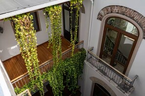 A multi-level interior with a wooden staircase, a balcony with a wrought iron railing, and a large arched window. - Los Diamantes (Panama City)