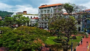 Un patio con un jardín central, rodeado de edificios de techos rojos y paredes blancas.