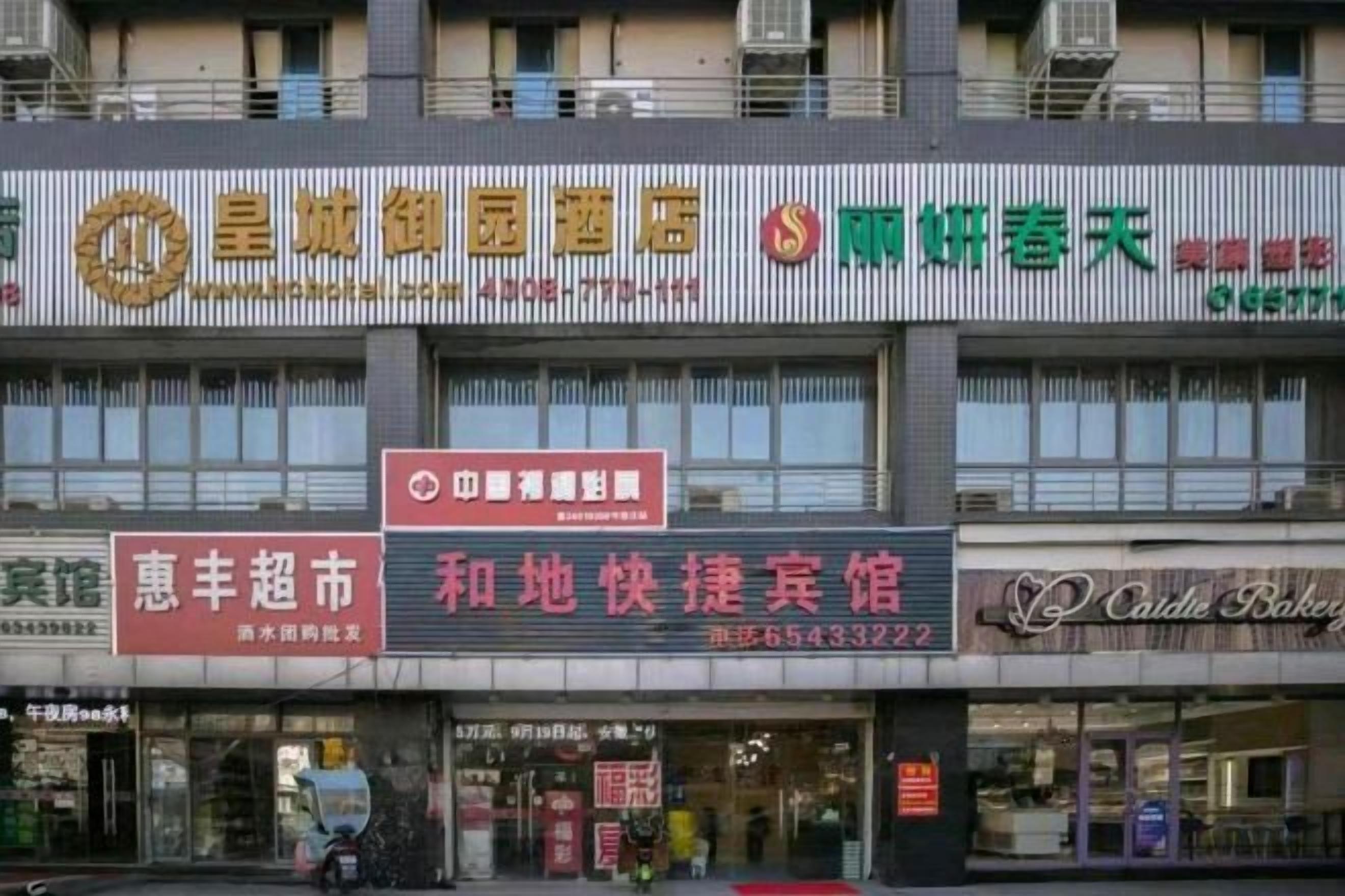 A multi-story building with various commercial establishments on the ground floor, including a pharmacy, a bakery, and a restaurant.