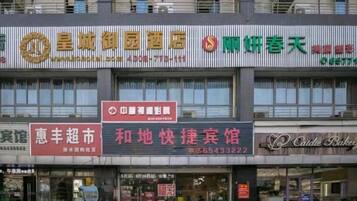 A multi-story building with various commercial establishments on the ground floor, including a pharmacy, a bakery, and a restaurant.