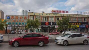 A street view with cars parked along the curb, buildings with commercial signage, and a clear sky.