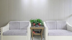 A room with two white sofas, a small table with a plant, and a framed picture on the wall. - Hedi Express Hotel, Hefei (Hefei)