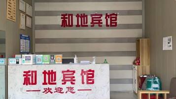 A reception desk with a sign, a staircase, and a small table with items on it.