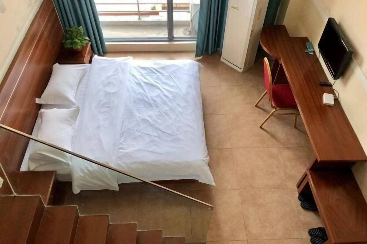 A hotel room with a bed, a desk, a chair, a TV, and a staircase.