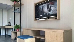A modern room with a TV mounted on the wall, a wooden desk, a small seating area, and a shelf with a plant. - Hedi Express Hotel, Hefei (Hefei)