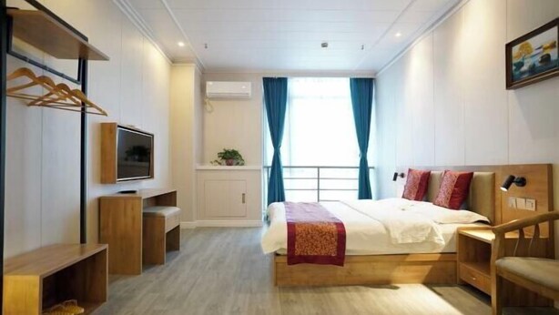 A modern hotel room with a bed, TV, wooden furniture, and a window with curtains. - Hedi Express Hotel, Hefei (Hefei)