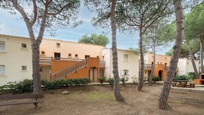 A courtyard with trees, a bench, and a building with a staircase. - Appartement with terrace, wifi, parking (Agde)