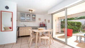 A kitchen with a dining area, a red microwave, and a sliding glass door leading to an outdoor patio. - Appartement with terrace, wifi, parking (Agde)