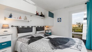Een slaapkamer met een bed, nachtkastjes, een raam met gordijnen en decoratieve wandversiering.