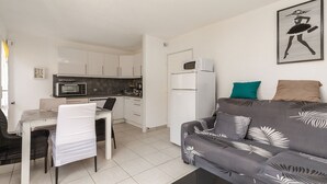 Een gezellig, compact verblijf met een kitchenette, een eethoek en een bank met opvallende kussens.
