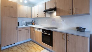A modern kitchen with wooden cabinets, a Bosch dishwasher, and a black range hood. - Studio 4 ppl, sea view balcony, pool, parking (Agde)