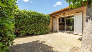 A house with a gravel driveway, a wooden deck, and a large hedge.