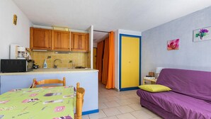A compact living space with a kitchenette, a dining area, and a sofa.