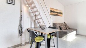 A modern interior with a dining table, chairs, a sofa, and a painting on the wall.