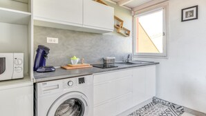 A compact kitchen with a washing machine, a coffee maker, and a sink.