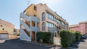 A multi-story residential building with a central staircase, balconies, and a parking area. - Modern apt 4 ppl, equipped loggia, pool (Agde)