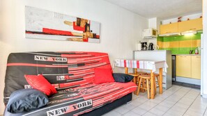 Sala de estar com sofá, mesa e área de cozinha.