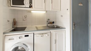 A compact kitchen with a washing machine, a microwave, and a sink. - Tiny house 4/6 ppl, terrace, private parking (Agde)