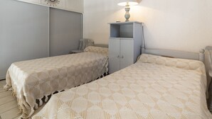 A bedroom with two beds, a wardrobe, a lamp, and a wall clock. - Tiny house 4/6 ppl, terrace, private parking (Agde)