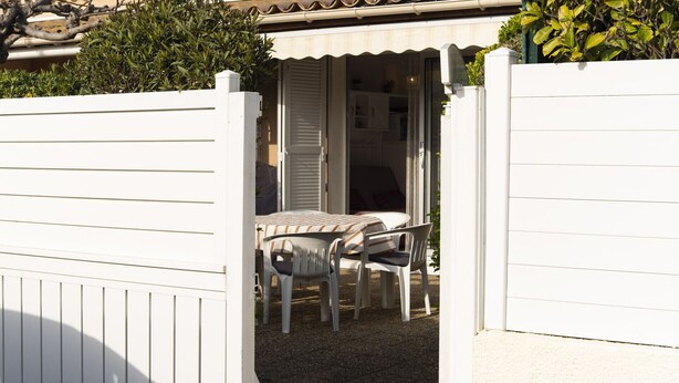 A white exterior wall with a small patio area featuring a table and chairs. - Tiny house 4/6 ppl, terrace, private parking (Agde)