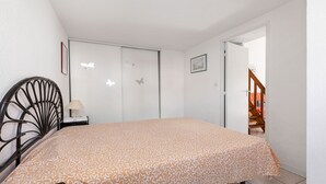 Une chambre à coucher comprenant un lit, une chaise, une table de chevet, une porte et un escalier.