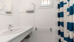 Une salle de bain avec un lavabo blanc, une fenêtre, un porte-serviettes et un rideau de douche.