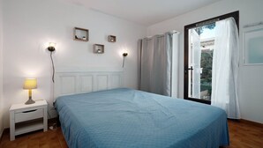 Une chambre à coucher comprenant un lit, une table de chevet, une lampe, des appliques murales et une fenêtre avec des rideaux.