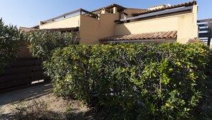 A residential building with a flat roof, a balcony, and a dense green hedge in front. - Apt 4 ppl, terrace, private parking (Agde)