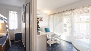 A compact room with a bunk bed, a small desk, a sofa, and a glass table. - Apt 4 ppl, terrace, private parking (Agde)