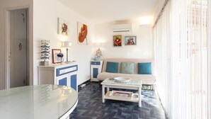 A living room with a sofa, a coffee table, a side table, and wall art. - Apt 4 ppl, terrace, private parking (Agde)