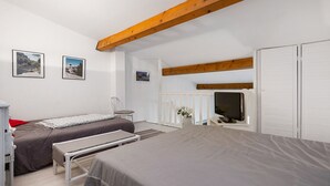 Een slaapkamer met twee bedden, een televisie en een witte kledingkast.
