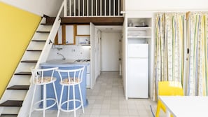 A compact kitchen with a dining area, a staircase, and a small refrigerator. - Studio 5 ppl, sea view balcony , pool, parking (Agde)