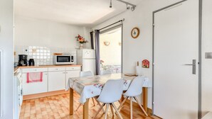 A compact kitchen with a microwave, coffee maker, and a dining table with chairs. - Bright apt 4/6 ppl, terrace, free parking (Agde)