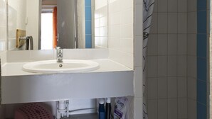 A bathroom with a white sink, a mirror, and a shower area. - Duplex house 4/6 ppl, terrace, near the sea (Agde)