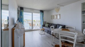 A modern bedroom with a balcony, a sofa, a dining table, and a fan. - Apartment for 6 people, lagoon view, balcony, pool, parking (Agde)