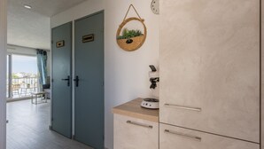Une cuisine moderne avec deux portes, une machine à café et un panier suspendu contenant des plantes.